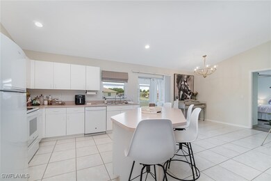 Kitchen with white appliances, a breakfast bar, li