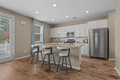 Kitchen featuring stainless steel appliances, a kitchen island with sink, decorative backsplash, white cabinets, and recessed lighting