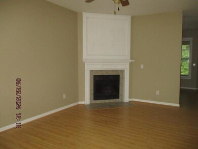 Unfurnished living room with a ceiling fan, wood finished floors, and a tiled fireplace