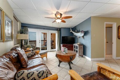 Living area with a drop ceiling, french doors, ceiling fan, and light tile patterned floors