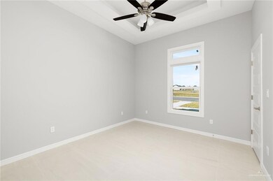 Spare room featuring a tray ceiling, baseboards, a ceiling fan, and light tile patterned flooring