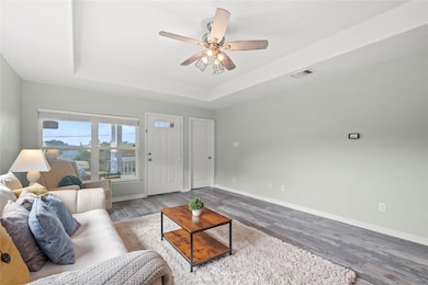 Living room featuring a raised ceiling, wood fini