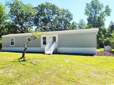 Manufactured / mobile home with a front lawn and a storage shed