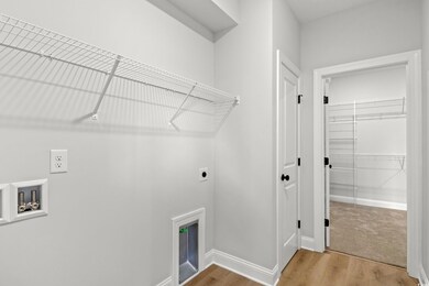 Clothes washing area with light wood-type flooring