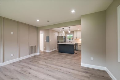 Unfurnished living room with light wood finished floors, electric panel, and recessed lighting