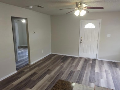 Entrance foyer featuring a textured ceiling, dark wood-type flooring, and a ceiling fan
