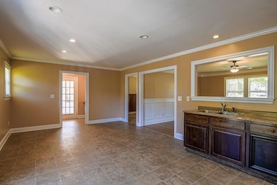 Kitchen with crown molding, dark brown cabinetry, recessed lighting, ceiling fan, and wainscoting