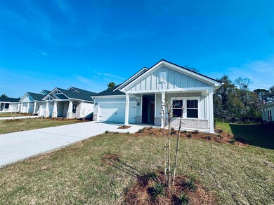 View of front of house with an attached garage, concrete driveway, a front yard, board and batten siding, and covered porch