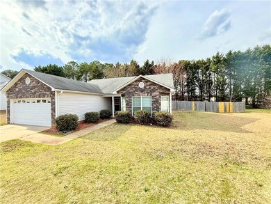 Ranch-style home featuring concrete driveway, ston
