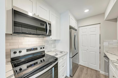 Kitchen with stainless steel appliances, white ca