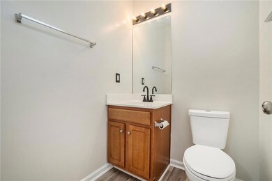 Half bathroom with vanity, toilet, baseboards, and wood finished floors