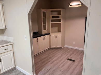 Kitchen with light wood-type flooring, baseboards, open shelves, and white cabinets