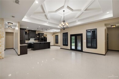 Kitchen featuring an inviting chandelier, beam ceiling, coffered ceiling, and light tile floors