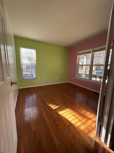 Spare room with dark wood-type flooring and baseboards