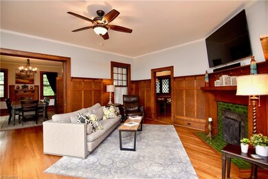 Formal living room has a coal burning fireplace and beautiful pocket doors. Wood floors and wainscot details.