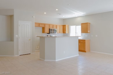 Kitchen featuring backsplash, light brown cabinets, a kitchen island, stainless steel microwave, and recessed lighting