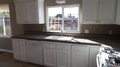 Kitchen sink area, cabinets, and tile countertops.