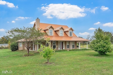 View of front of property featuring a chimney, a front yard, covered porch, and a metal roof