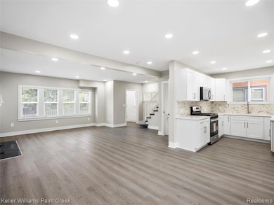 Kitchen with white cabinets, stainless steel appliances, backsplash, light wood-type flooring, and plenty of natural light