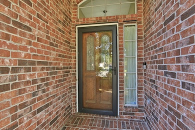 Charming brick entryway featuring a wood door with decorative glass panels, flanked by a tall, narrow window.