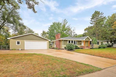 Front view of home, oversized 2 car garage and concrete drive with additional parking. Note fenced garden or kennel to left of garage.