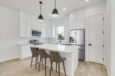 Open kitchen with stainless steel appliances and quartz counters.