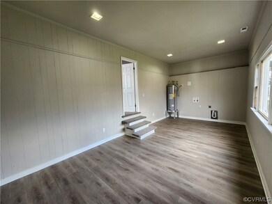 Empty room featuring electric water heater and hardwood / wood-style flooring