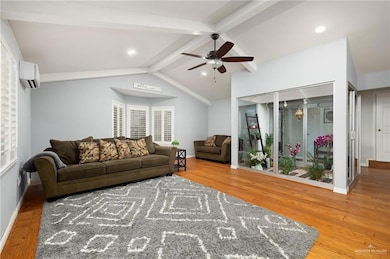 Living area with a ceiling fan, wood finished floors, an AC wall unit, and recessed lighting