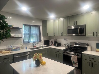 Kitchen featuring stainless steel appliances, a sink, decorative backsplash, and light stone counters