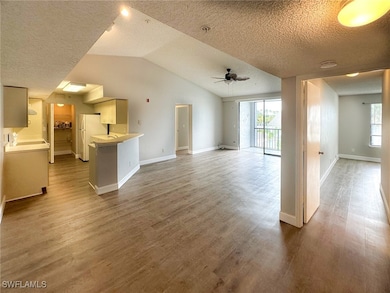 Unfurnished living room featuring a textured ceiling, light wood-style floors, ceiling fan, and vaulted ceiling