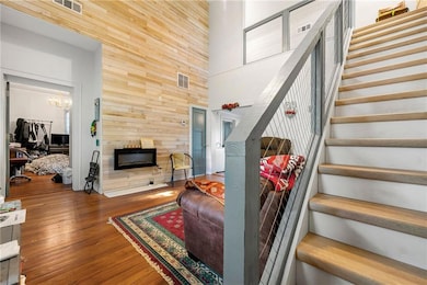 Stairway featuring a towering ceiling, wood walls, wood finished floors, a chandelier, and a fireplace