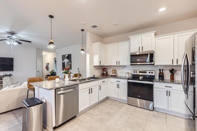 Kitchen with stainless steel appliances, open floor plan, tasteful backsplash, white cabinets, and a ceiling fan