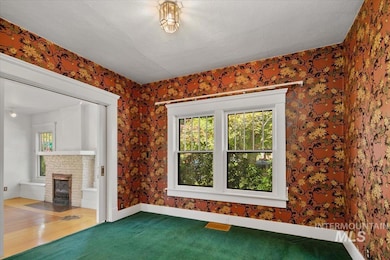 Unfurnished living room featuring healthy amount of natural light, a brick fireplace, carpet floors, and wallpapered walls