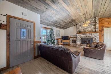 Living area with wooden walls, a wainscoted wall, vaulted ceiling, wood-type flooring, and wood ceiling