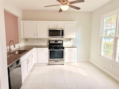 Kitchen featuring appliances with stainless steel finishes, dark stone counters, white cabinetry, and decorative backsplash