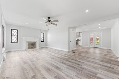 Unfurnished living room featuring a high end fireplace, ceiling fan, light hardwood / wood-style floors, and french doors
