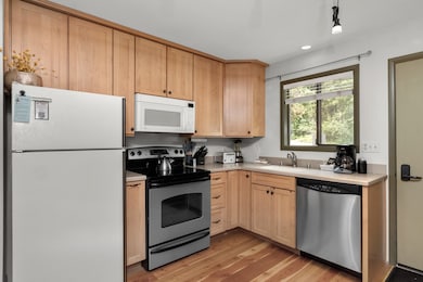 Kitchen featuring appliances with stainless steel finishes, light brown cabinets, light countertops, and light wood-style flooring