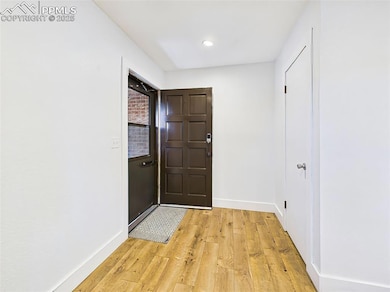 Bright and simple entryway with recessed lighting and wide-plank wood-style flooring that flows throughout the main level.