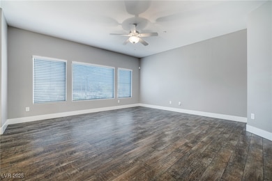 Unfurnished room with a ceiling fan and dark wood-