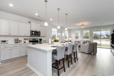 Kitchen with appliances with stainless steel finishes, a kitchen bar, light countertops, light wood-type flooring, and an island with sink