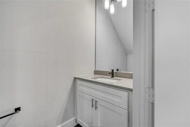 Bathroom with vaulted ceiling, vanity, and baseboa