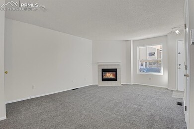 Unfurnished living room with carpet flooring, a tiled fireplace, and a textured ceiling