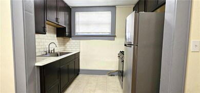 Kitchen with freestanding refrigerator, a sink, light countertops, decorative backsplash, and baseboards
