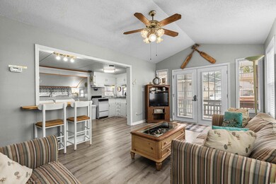 Living room with light wood-style flooring, ceiling fan, lofted ceiling, baseboards, and a textured ceiling