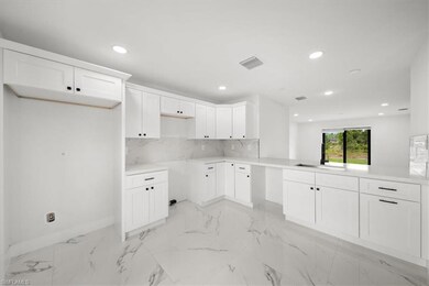 Kitchen with a sink, backsplash, recessed lighting, baseboards, and white cabinetry