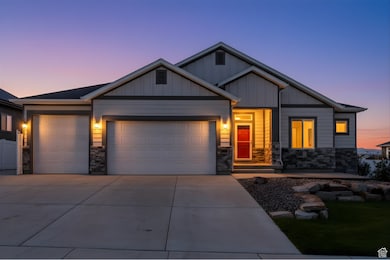 View of front facade featuring stone siding, an attached garage, concrete driveway, and board and batten siding
