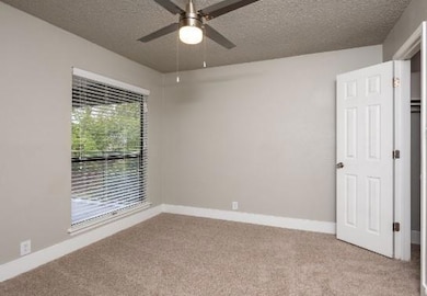 Carpeted empty room featuring ceiling fan and a te