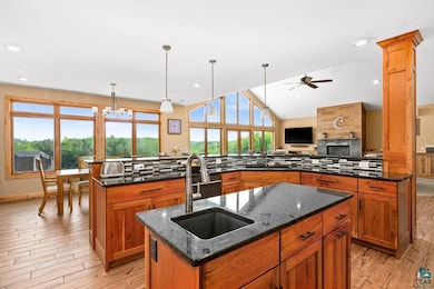 Kitchen with a center island with sink, a sink, ceiling fan, tasteful backsplash, and vaulted ceiling