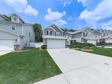View of front of property with a garage, concrete driveway, a residential view, and stone siding