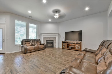 Living area featuring a ceiling fan, wood finished floors, recessed lighting, and a fireplace